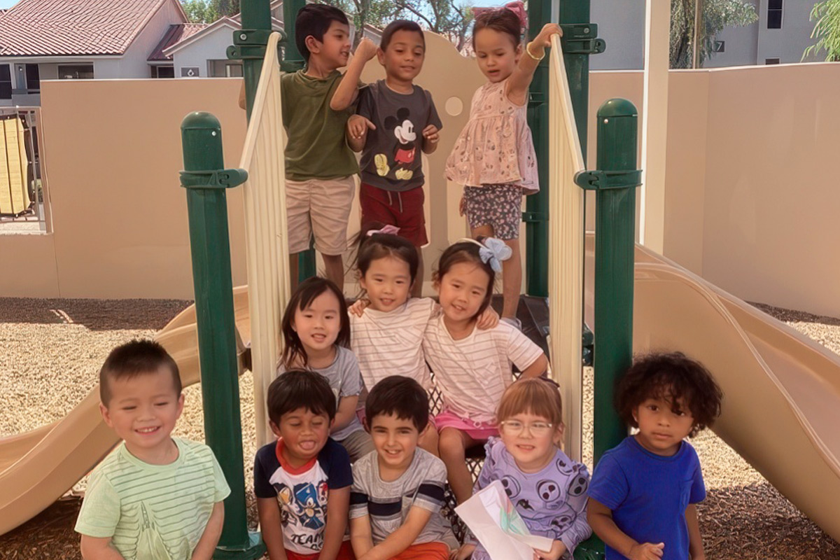 Group of happy children on a playground slide at ElevateChild preschool in Scottsdale, AZ.