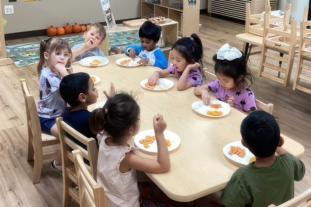 Group of diverse preschoolers eating snacks at a table at ElevateChild childcare in Scottsdale, AZ.